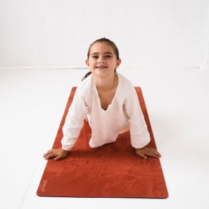 child laying on pilates mat smiling