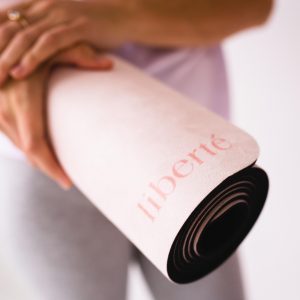 lady holding rolled up pilates mat with liberte logo