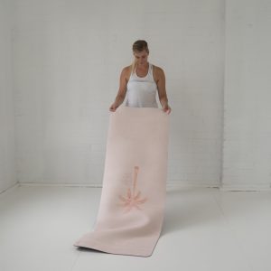 lady unrolling pilates mat with palm tree